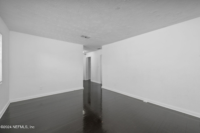 unfurnished room featuring a textured ceiling and dark wood-type flooring