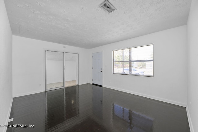 empty room featuring a textured ceiling and dark wood-type flooring