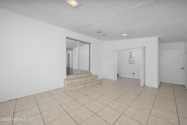 tiled spare room with a textured ceiling