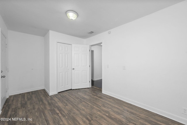 unfurnished bedroom featuring dark hardwood / wood-style flooring and a closet