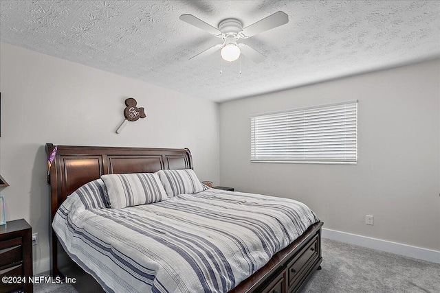 carpeted bedroom featuring ceiling fan and a textured ceiling