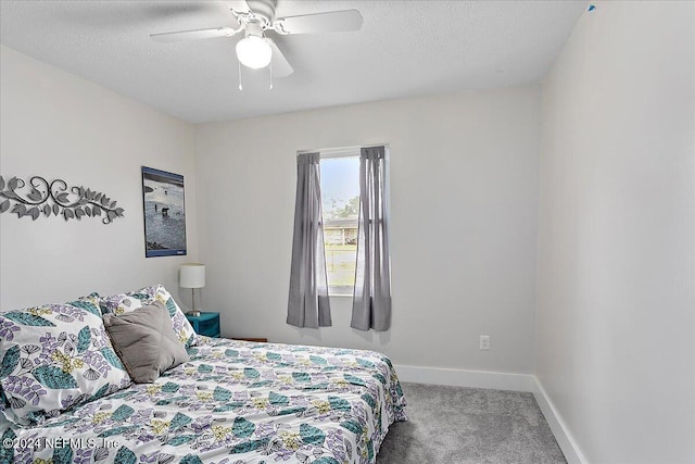 carpeted bedroom with ceiling fan and a textured ceiling