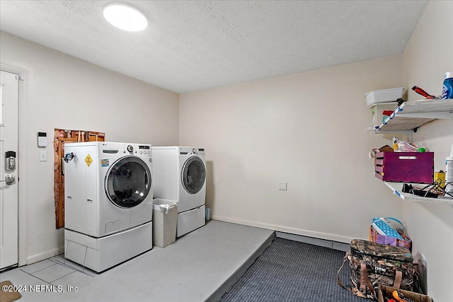 clothes washing area featuring a textured ceiling, washing machine and dryer, and light tile patterned floors