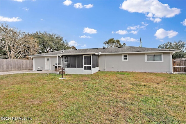 rear view of house featuring a sunroom and a yard