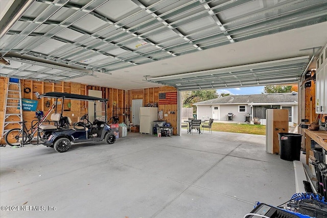 garage with white fridge and wood walls