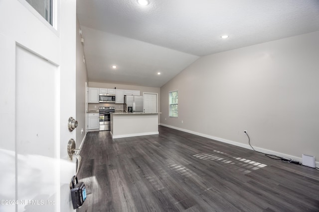 unfurnished living room with a textured ceiling, vaulted ceiling, and dark wood-type flooring