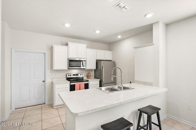 kitchen with white cabinets, a kitchen breakfast bar, sink, kitchen peninsula, and stainless steel appliances