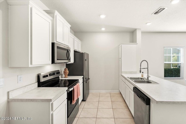 kitchen with sink, stainless steel appliances, light tile patterned floors, kitchen peninsula, and white cabinets