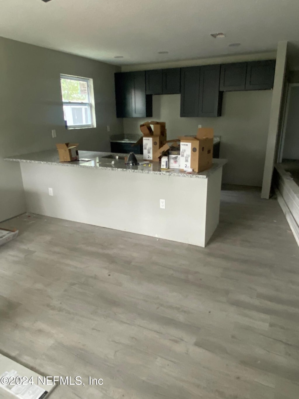 kitchen with light stone counters, kitchen peninsula, and light hardwood / wood-style flooring