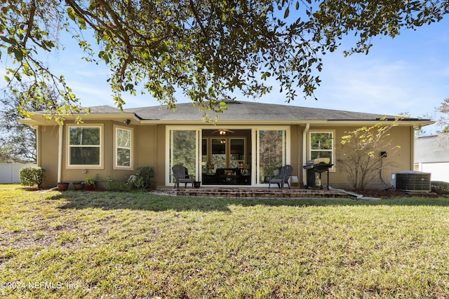 rear view of property featuring central AC and a lawn