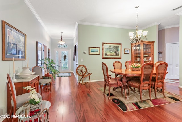 dining area featuring wood-type flooring, ornamental molding, and a chandelier