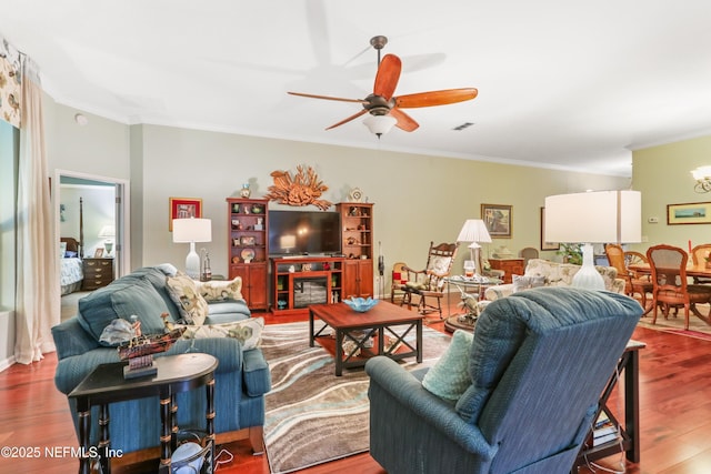 living room featuring hardwood / wood-style flooring, ornamental molding, and ceiling fan