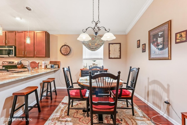 dining room with sink, crown molding, a chandelier, and dark hardwood / wood-style floors