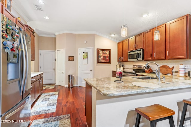 kitchen with kitchen peninsula, pendant lighting, appliances with stainless steel finishes, ornamental molding, and sink