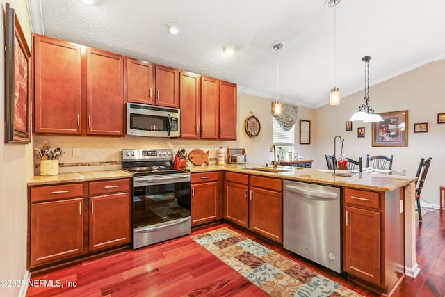 kitchen with stainless steel appliances, kitchen peninsula, ornamental molding, sink, and decorative light fixtures