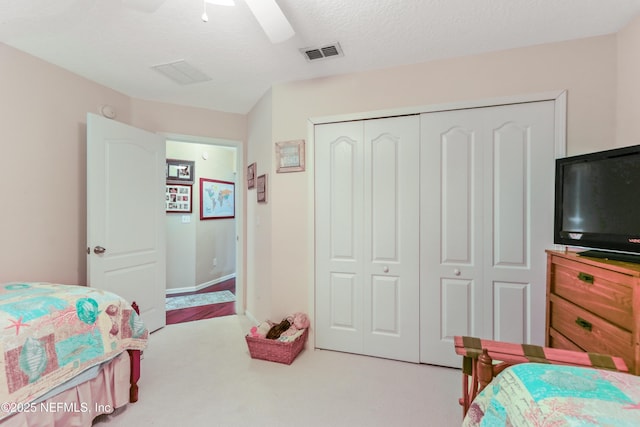 bedroom with a closet, ceiling fan, a textured ceiling, and light colored carpet