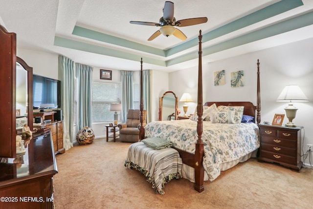 bedroom with carpet floors, ceiling fan, and a tray ceiling