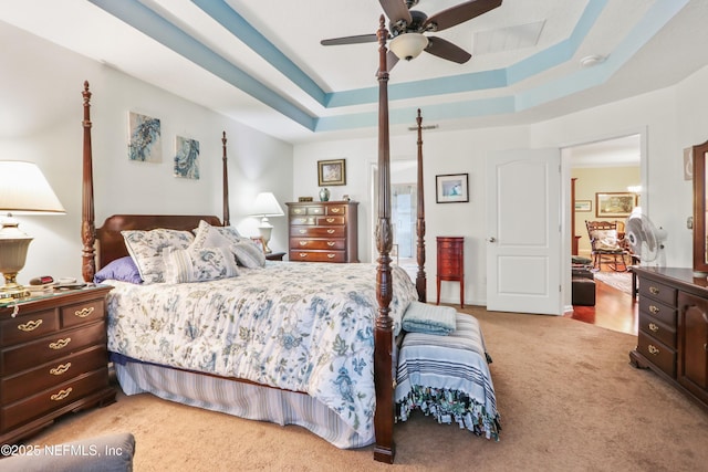 bedroom with ceiling fan, light colored carpet, and a raised ceiling