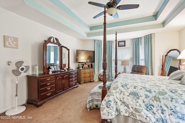 bedroom with light carpet, ceiling fan, and a tray ceiling