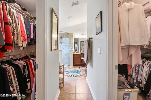 walk in closet featuring light tile patterned flooring and vaulted ceiling