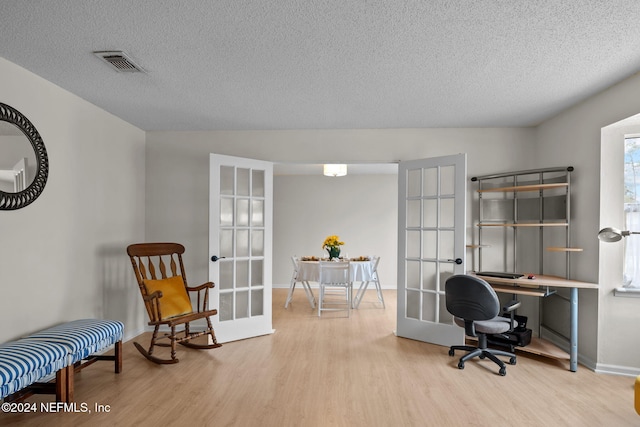 office area featuring light hardwood / wood-style floors, a textured ceiling, and french doors