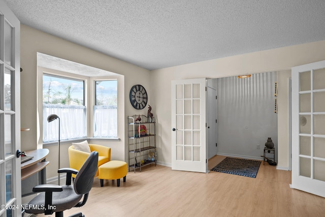 office space featuring french doors, light wood-type flooring, and a textured ceiling