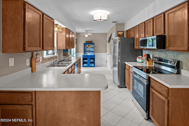 kitchen with kitchen peninsula, appliances with stainless steel finishes, tasteful backsplash, ceiling fan, and sink