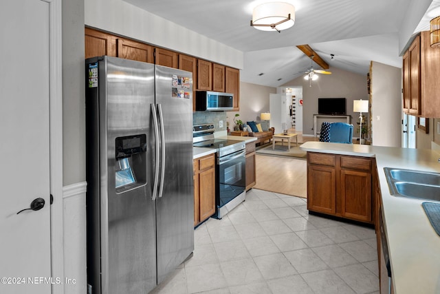 kitchen with appliances with stainless steel finishes, tasteful backsplash, ceiling fan, sink, and vaulted ceiling with beams