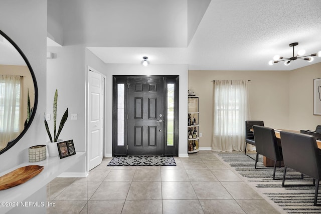 tiled entrance foyer featuring a textured ceiling and an inviting chandelier