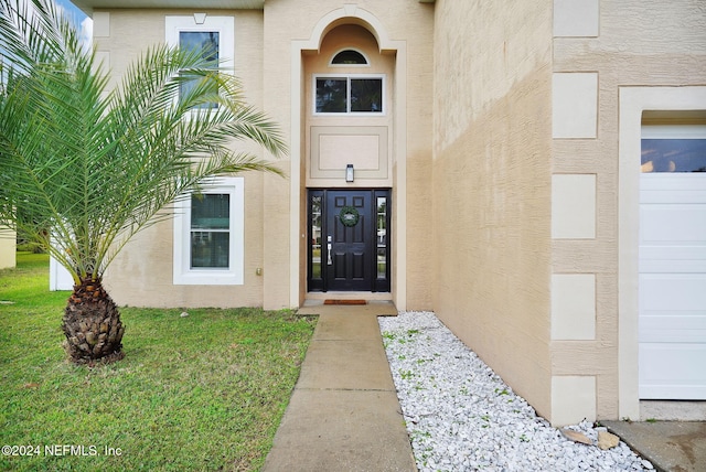 view of exterior entry with a yard