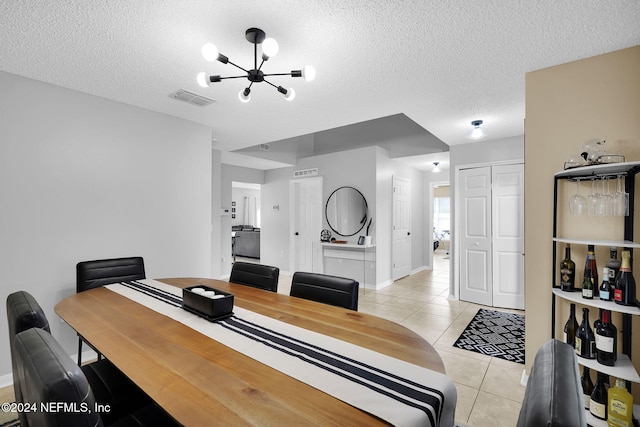 tiled dining area with a notable chandelier and a textured ceiling