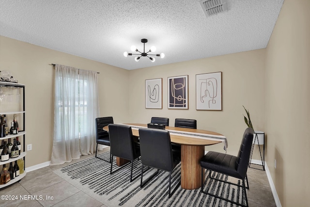 tiled dining area with a chandelier and a textured ceiling