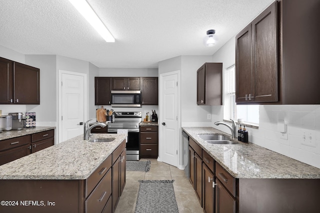 kitchen with a textured ceiling, dark brown cabinets, sink, and stainless steel appliances