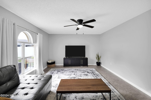 living room featuring ceiling fan, tile patterned flooring, and a textured ceiling