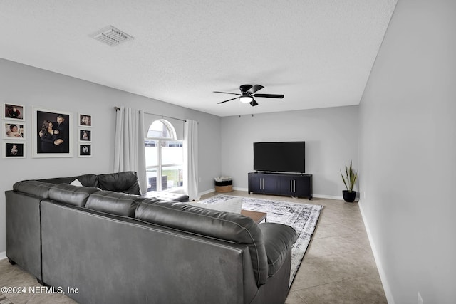 living room featuring ceiling fan, light tile patterned floors, and a textured ceiling