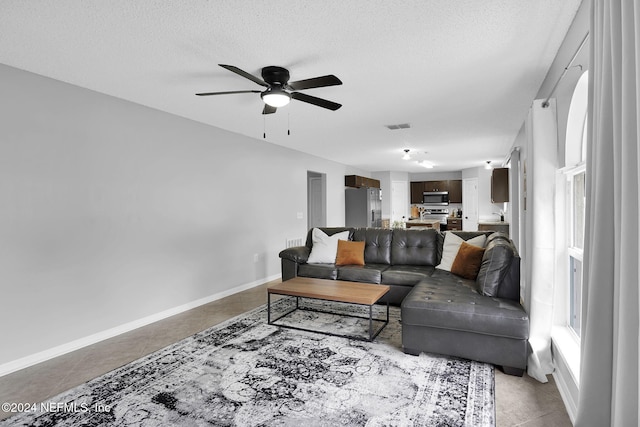 living room featuring ceiling fan and a textured ceiling