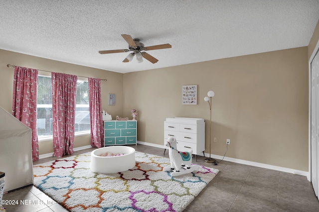 tiled bedroom featuring ceiling fan and a textured ceiling