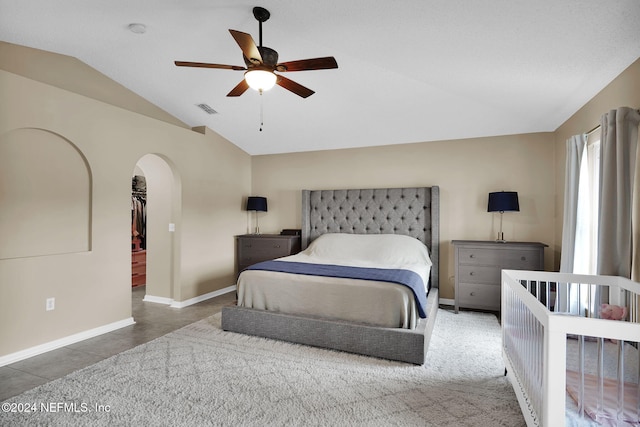 bedroom with ceiling fan, dark tile patterned floors, and vaulted ceiling