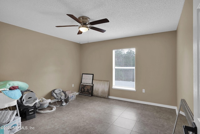 misc room featuring ceiling fan, light tile patterned floors, and a textured ceiling