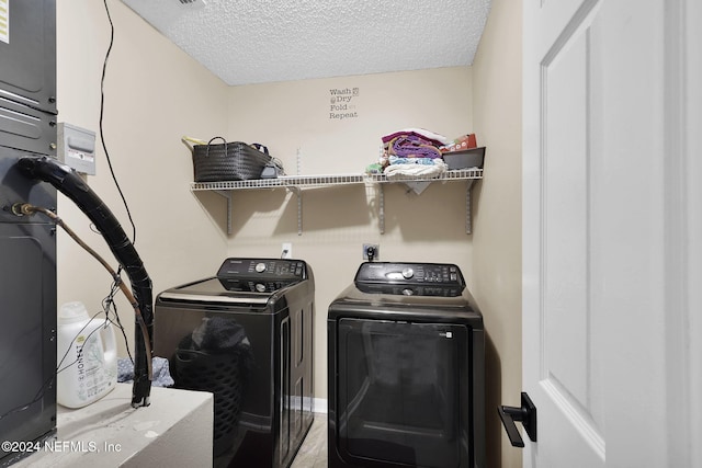 laundry room with a textured ceiling and washer and clothes dryer