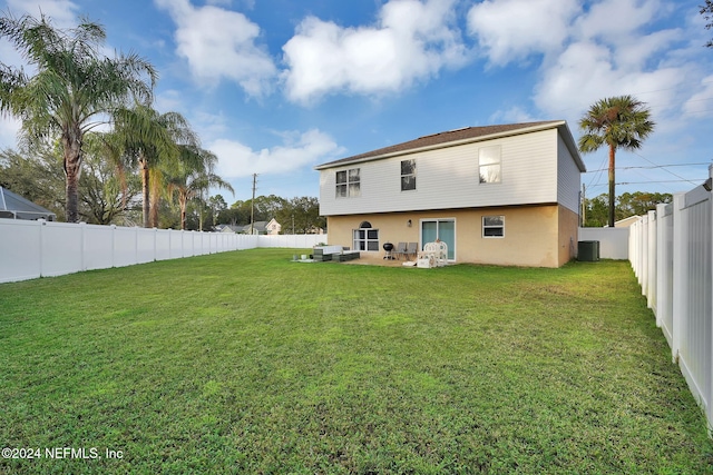 rear view of house with a yard, central AC, and a patio area