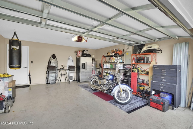 garage featuring stainless steel refrigerator with ice dispenser and a garage door opener