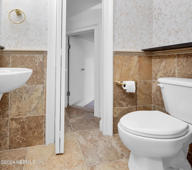 bathroom with toilet and tile walls