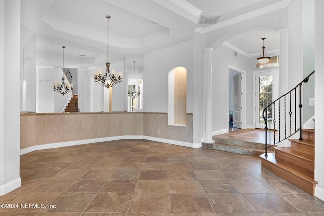 foyer entrance with a chandelier, a raised ceiling, and crown molding