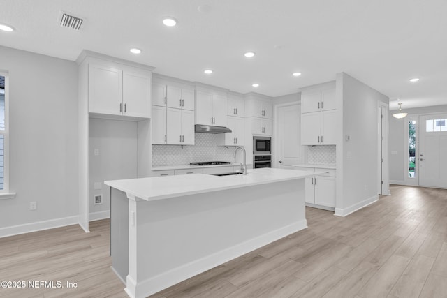 118 Caiden Dr, Ponte Vedra, FL 32081 - kitchen with under cabinet range hood, stainless steel microwave, a sink, light wood-type flooring, and recessed lighting