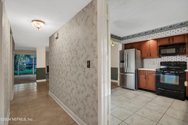 kitchen with light tile patterned flooring, black appliances, and a textured ceiling