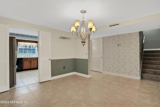 empty room featuring a chandelier, light tile patterned floors, and sink