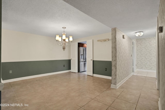 unfurnished room featuring a textured ceiling and a notable chandelier