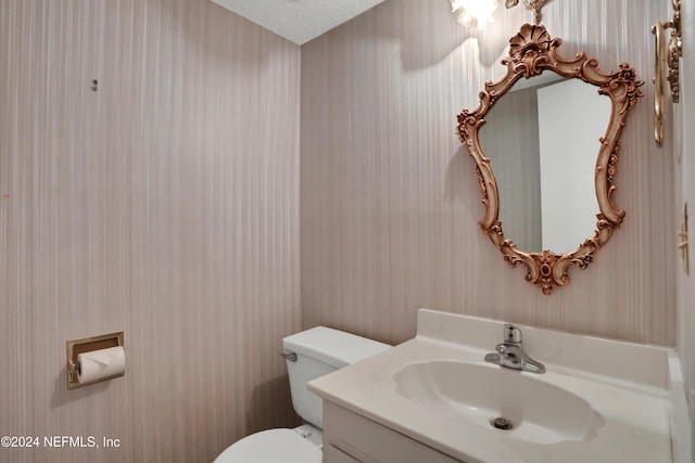 bathroom featuring vanity, a textured ceiling, and toilet