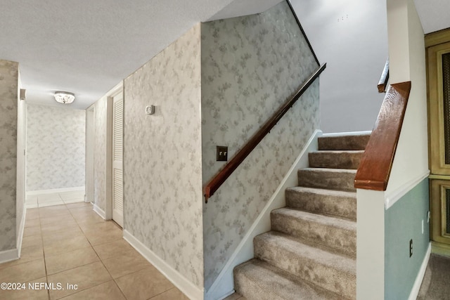 staircase with tile patterned floors and a textured ceiling